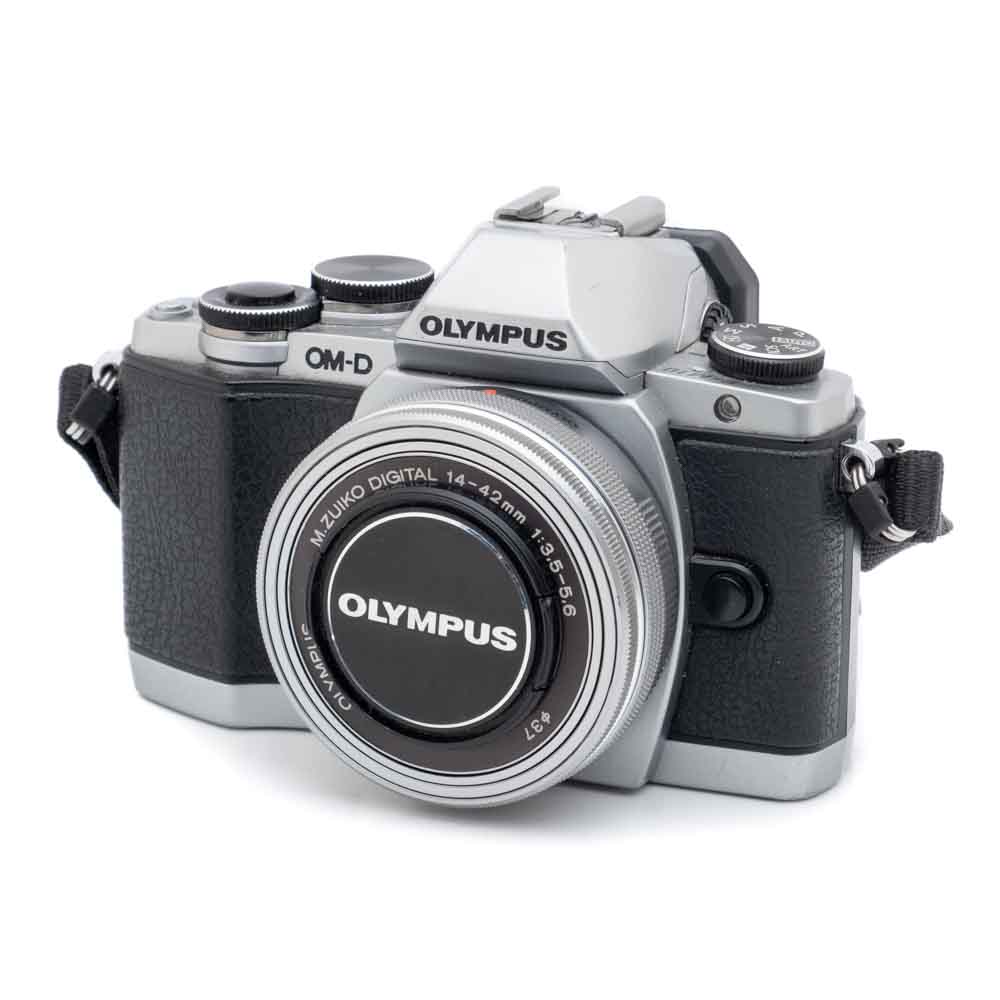 Olympus OM-D E-M10-kit-1 Hopeanmusta Olympus OM-D E-M10 (SC 7000) -digitaalikamera, jossa on M.Zuiko Digital 14-42mm f/3.5-5.6 -objektiivi (Käytetty), edestäpäin valkoisella pohjalla.
