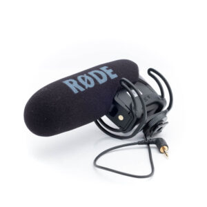 Rode Videomic Pro-1 Käytetty Rode VideoMic Pro (Kunto K5), jossa on musta vaahtomuovinen tuulisuoja ja iskukiinnike, 3,5 mm:n ääniliitin kiinnitettynä, näytetään valkoisella pohjalla.