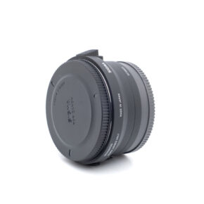 Sigma MC-11-1 Käytetty Sigma MC-11 -sovitin seisoo pystyssä valkoisella pohjalla, ja sen molemmat päät on suljettu. Se on musta ja siinä on Sigma- ja Made in Japan -merkintä.