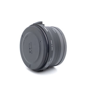 Käytetty Sigma MC-11 -sovitin seisoo pystyssä valkoisella pohjalla, ja sen molemmat päät on suljettu. Se on musta ja siinä on Sigma- ja Made in Japan -merkintä.