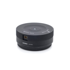 Sigma USB-dock Canon-1 Käytetty Sigma USB-Dock Canon (sis.ALV24%) -lisävaruste, musta USB-portilla ja merkinnällä FOR CANON ja SIGMA UD-01E0, näkyy valkoisella pohjalla.