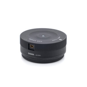 Käytetty Sigma USB-Dock Canon (sis.ALV24%) -lisävaruste, musta USB-portilla ja merkinnällä FOR CANON ja SIGMA UD-01E0, näkyy valkoisella pohjalla.