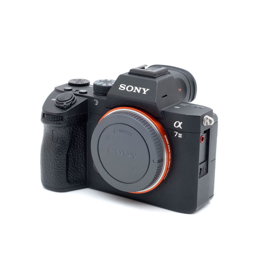 Sony A7 III-2-1 Sony A7 III (SC 26500) - Käytetty -peilittömän kameran runko näkyy edestä vasemmalta, ja siinä on objektiivin kiinnityssuojus sekä näkyvät säätimet ja painikkeet.