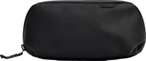 800q-01_128331 Mustassa Peak Design Tech Pouch Small -laukussa on sileä rakenne, minimaalinen tuotemerkintä ja pieni tunniste vetoketjun vieressä vaaleaa taustaa vasten.