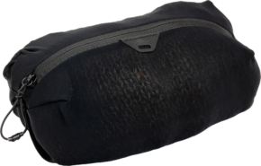 800q-01_128338 The black Peak Design Ultralight Mesh Packing Cube X-Small features a textured front, rounded edges, a zippered closure with a drawstring with a looped cord at the zipper, and is patterned against a plain background.