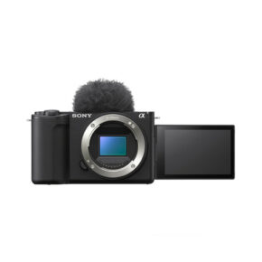 Sony ZV-E10 II -järjestelmäkamerassa, jossa ei ole objektiivia, on ulos käännettävä LCD-näyttö ja sen päälle on kiinnitetty pörröinen mikrofonin tuulisuoja, joka näkyy valkoista taustaa vasten.