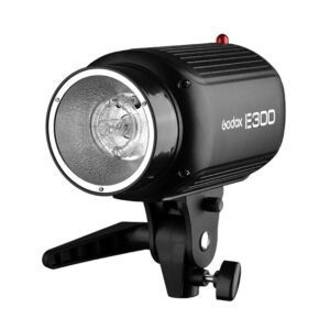 1455103160_121 Musta Godox Studio Kit E300 D -studiosalama stroboskooppisalama, jossa on hopeinen heijastin, kiinnike ja säätönuppi, kuvattuna kulmasta valkoista taustaa vasten.