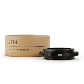 1677857206_132 Musta Urth Tamron T Mount to Canon (EF/EF S) objektiiviadapteri on sijoitettu pyöreän, ruskean pahvilaatikon eteen, jossa on merkintä URTH Lens Mount Adapter valkoisella pohjalla.