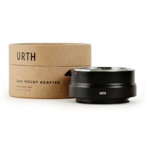 1678090079_522 Musta Urth Nikon F - Canon RF objektiiviadapteri lepää sen sylinterimäisen ruskean pahvilaatikon vieressä, jossa lukee "Urth Lens Mount Adapter" englanniksi ja japaniksi.