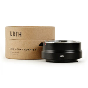 1678090079_522 Musta Urth Nikon F - Canon RF objektiiviadapteri lepää sen sylinterimäisen ruskean pahvilaatikon vieressä, jossa lukee "Urth Lens Mount Adapter" englanniksi ja japaniksi.