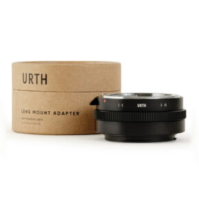 1678090093_679 Musta Urth Nikon F (G-tyyppi) - Canon RF objektiiviadapteri istuu sen lieriömäisen ruskean pahvipakkauksen vieressä, jossa on merkintä URTH-objektiiviasennussovitin valkoisella pohjalla.