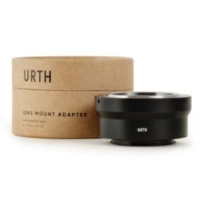1678090320_416 Musta Urth M42 - Fujifilm X objektiiviadapteri istuu sen sylinterimäisen pahvipakkauksen vieressä, jossa lukee "Lens Mount Adapter" ja "Urth" suurilla kirjaimilla valkoisella pohjalla.