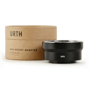 1678090347_348 Musta Urth Olympus OM - Fujifilm X objektiiviadapteri näkyy sen sylinterimäisen ruskean pahvipakkauksen vieressä, jossa on merkintä URTH Lens Mount Adapter; adapteri on tyylikäs ja kompakti.