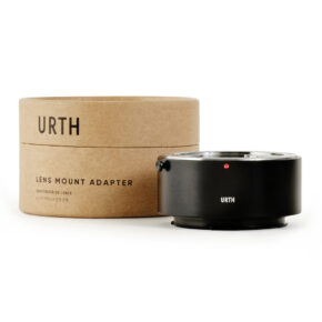 1678090394_788 Lieriömäinen pahvilaatikko, jossa lukee "Urth Contax/Yashica (C/Y) - Leica L objektiiviadapteri", on mustan metallisen URTH-logolla varustetun objektiiviasennussovittimen vieressä, ja molemmat ovat valkoisella pohjalla.