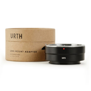 Musta Urth Canon (EF / EF S) - Leica L objektiiviadapteri näytetään sen ruskean lieriömäisen pakkauksen vieressä, jossa on merkintä URTH Lens Mount Adapter valkoisella taustalla.
