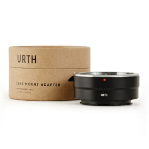 1678090407_665 Musta Urth Canon (EF / EF S) - Leica L objektiiviadapteri näytetään sen ruskean lieriömäisen pakkauksen vieressä, jossa on merkintä URTH Lens Mount Adapter valkoisella taustalla.