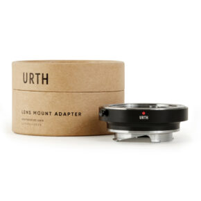 1678090581_721 Urth Contax/Yashica (C/Y) - Leica M objektiiviadapteri näkyy lieriömäisen ruskean pakkauksen edessä, jossa lukee "URTH LENS MOUNT ADAPTER". Sovittimessa on musta ja hopeinen viimeistely, jossa on punainen kohdistuspiste.