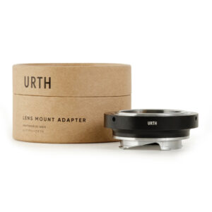 1678090672_186 Lieriömäinen pahvilaatikko, jossa lukee "Urth M42 - Leica M objektiiviadapteri", on metallisen objektiiviasennussovittimen vieressä, ja molemmissa on Urthin logo valkoista taustaa vasten.