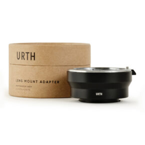 1678090884_988 Musta Urth Leica R - Micro Four Thirds (M4/3) objektiiviadapteri istuu sen pyöreän, ruskean pahvilaatikon edessä, jossa lukee lihavoituna "URTH LENS MOUNT ADAPTER".