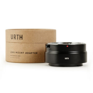 1678091067_320 Musta Urth Contax/Yashica (C/Y) - Nikon Z objektiiviadapteri näkyy sen lieriömäisen ruskean pahvisen pakkauksen vieressä, jossa on merkintä "Urth Lens Mount Adapter" valkoisella pohjalla.