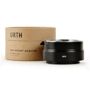 1678091095_457 Musta Urth Nikon F - Nikon Z objektiiviadapteri istuu sen lieriömäisen pahvipakkauksen vieressä, jossa on merkintä URTH Lens Mount Adapter valkoista taustaa vasten.