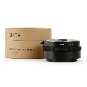 Urth Nikon F (G-tyyppi) - Nikon Z objektiiviadapteri istuu sen pyöreä, ruskea pahvilaatikko merkitty "Lens Mount Adapter" Englanti ja Japani. Mustassa sovittimessa on harjanteet ja Urth-logo.
