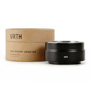1678091181_957 Musta Urth Olympus OM - Nikon Z objektiiviadapteri istuu sen ruskean sylinterimäisen pahvipakkauksen vieressä, jossa on merkintä URTH LENS MOUNT ADAPTERI valkoisella taustalla.