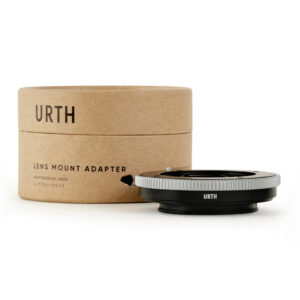 1678091934_038 Urth Contax G - Sony E objektiiviadapteri on sijoitettu edessä sen lieriömäinen ruskea pahvipakkaus merkitty URTH ja LENS MOUNT ADAPTER mustalla tekstillä.