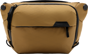 800q-01_127961 Peak Design Everyday Sling v2 3L - Coyote on ruskehtava, säänkestävä laukku, jossa on mustat korostukset, vetoketjullinen etutasku ja timanttikuvioinen kangas, joka näkyy yksiväristä taustaa vasten.