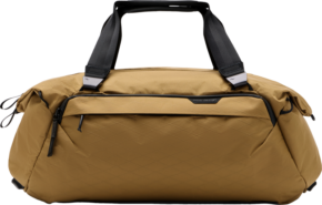 800q-01_127966 Peak Design Travel Duffel 35L - Coyote -laukussa on mustat kahvat ja vetoketjut, timanttikuvioinen rakenne ja vetoketjullinen etutasku, joka näkyy vaalealla pohjalla.