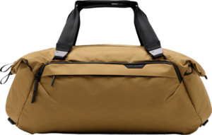 800q-01_127966 Peak Design Travel Duffel 35L - Coyote -laukussa on mustat kahvat ja vetoketjut, timanttikuvioinen rakenne ja vetoketjullinen etutasku, joka näkyy vaalealla pohjalla.