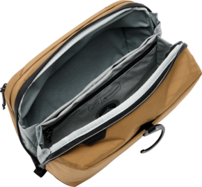 800q-01_127968 Peak Design Wash Pouch - Coyote on avattu, jolloin paljastuu tilava sisustus, jossa on useita harmaita ja mustia lokeroita ja taskuja, mukaan lukien pehmustettu holkki kannettavalle tietokoneelle tai tabletille.