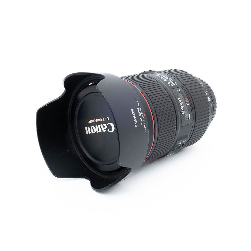 Canon 24-70 L IS USM II-3 Canon 24-105mm f/4 L IS II USM - Käytetty objektiivi, johon on kiinnitetty vastavalosuoja, on sijoitettu valkoiselle taustalle. Canon-logo ja objektiivin tiedot näkyvät selvästi etusuljessa.