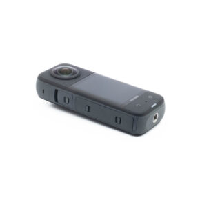Insta360 X3-2 Insta360 X3 (sis. ALV 25,5%) - Käytetty on kompakti musta 360 asteen toimintakamera, jossa on suuri objektiivi, näyttö ja sivupainikkeet valkoisella pohjalla.