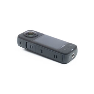 Insta360 X3-2 Insta360 X3 (sis. ALV 25,5%) - Käytetty on kompakti musta 360 asteen toimintakamera, jossa on suuri objektiivi, näyttö ja sivupainikkeet valkoisella pohjalla.