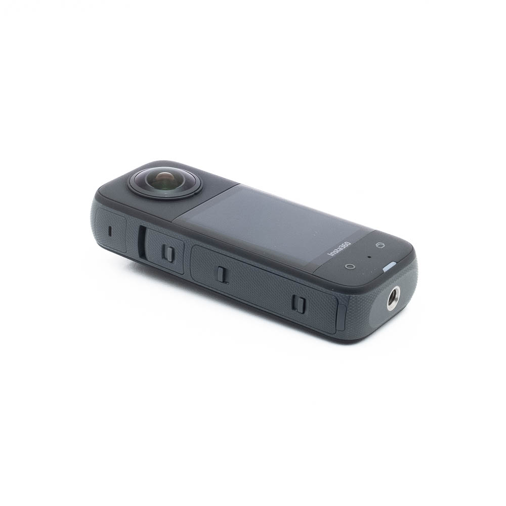 Insta360 X3-2 Insta360 X3 (sis. ALV 25,5%) - Käytetty on kompakti musta 360 asteen toimintakamera, jossa on suuri objektiivi, näyttö ja sivupainikkeet valkoisella pohjalla.