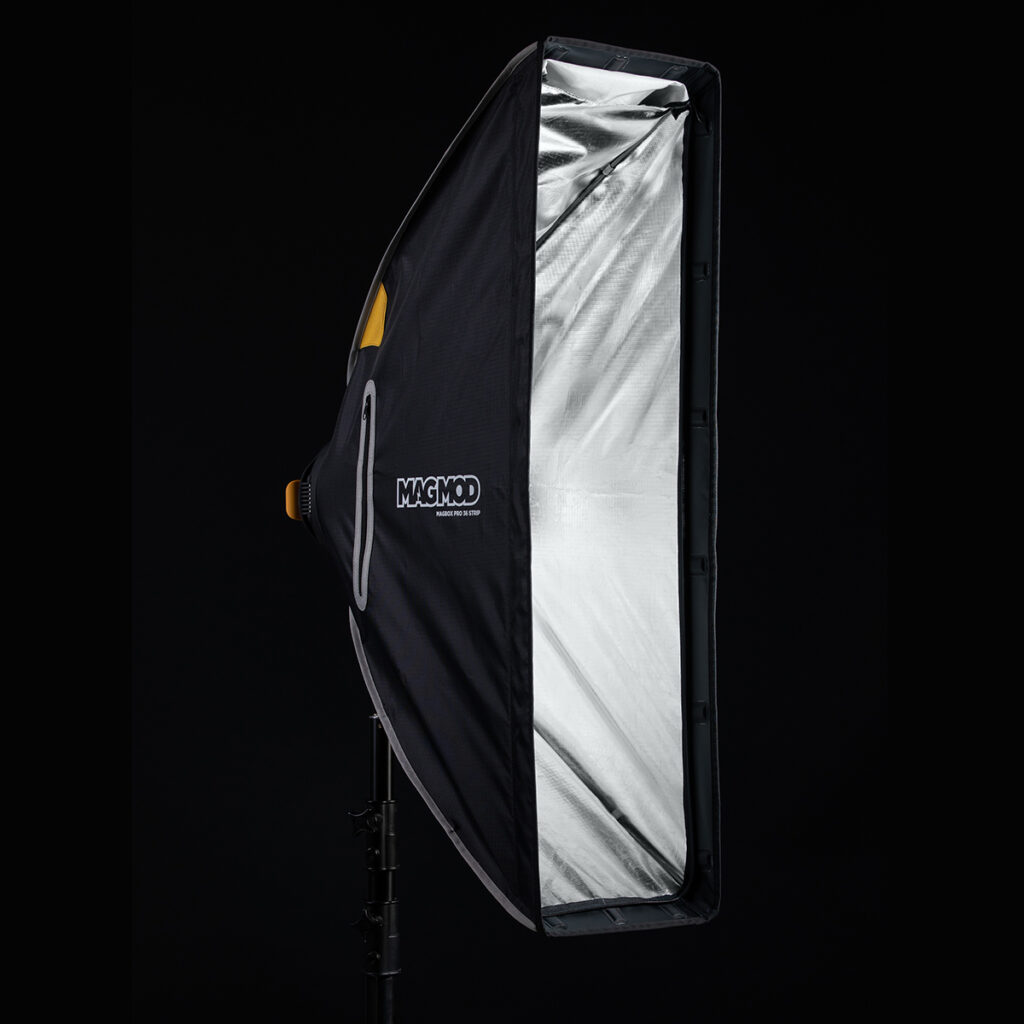 1623067668_348 MagMod MagBox Pro 36 Strip, suorakulmainen softbox, jossa on heijastava hopeinen sisäpuoli, on asennettu valotelineeseen mustaa taustaa vasten valokuvausvalaistusta varten.
