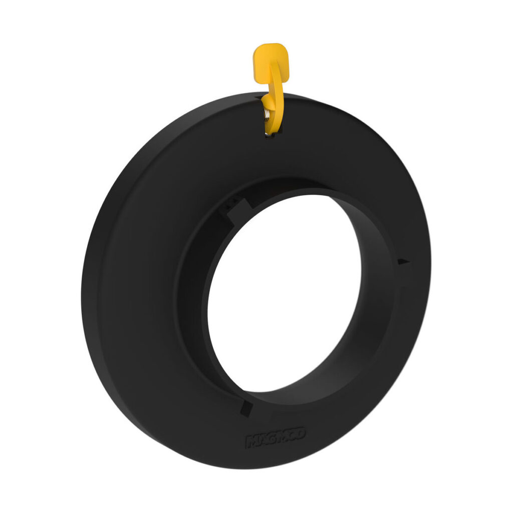 1680081324_015 MagMod Speedring Pro for Bowens on musta pyöreä muovinen lisävaruste, jossa on suuri keskireikä ja pieni keltainen koukku yläosassa.
