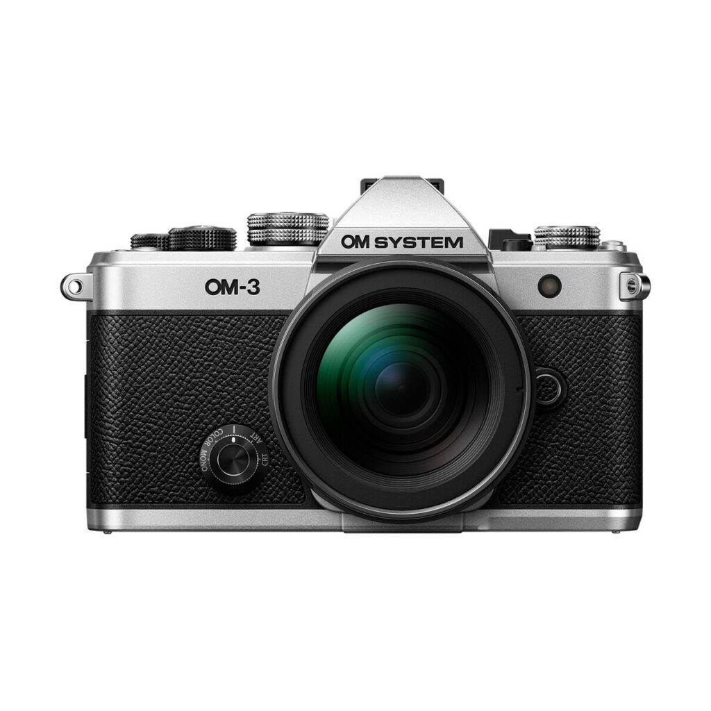om-3_12-45mm_03 Hopean ja mustan värisen OM System OM-3 + 12-45mm f/4 Pro -kameran etukuva, jossa on suuri objektiivi, yksityiskohtaiset painikkeet, valitsimet ja kuvioitu kahva, eristettynä valkoiselle taustalle.