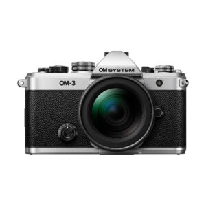 Hopean ja mustan värisen OM System OM-3 + 12-45mm f/4 Pro -kameran etukuva, jossa on suuri objektiivi, yksityiskohtaiset painikkeet, valitsimet ja kuvioitu kahva, eristettynä valkoiselle taustalle.