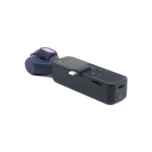DJI Osmo Pocket - Käytetty on pienikokoinen musta käsikäyttöinen gimbaalikamera, jossa on pieni näyttö, ohjauspainikkeet, USB-C-portti ja sisäänrakennettu vakain, kuvassa valkoisella pohjalla.