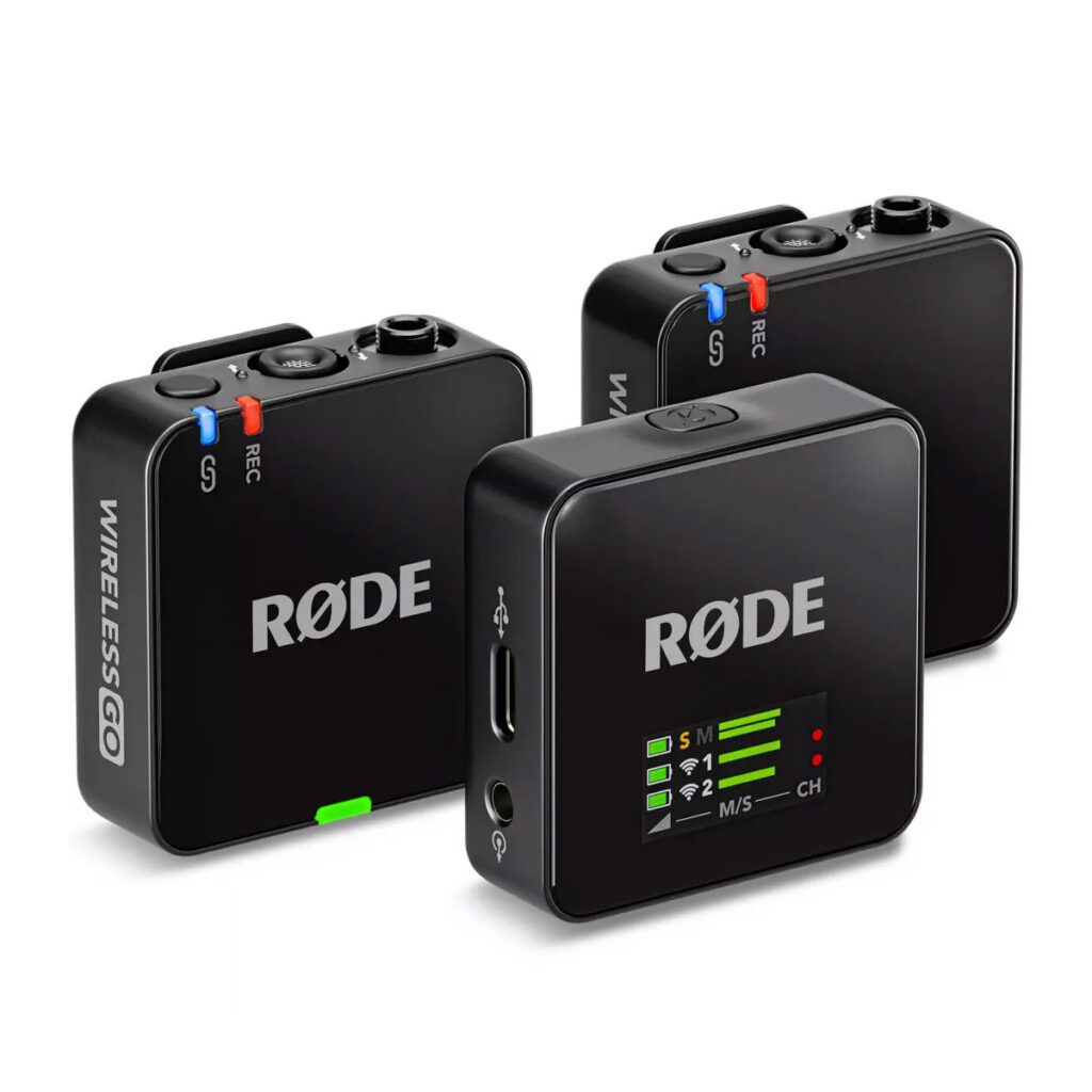 wireless_go_gen3_04 Kolme mustaa Rode Wireless GO III -langaton mikrofonijärjestelmä -yksikköä, joissa on säätimet, LED-merkkivalot ja portit, on sijoitettu valkoiselle taustalle, ja RØDE-logo näkyy jokaisessa laitteessa.
