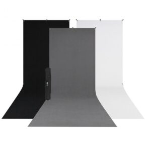 1572520829_519 Westcott X Drop 3 Pack Sweep Backdrop Kit (1.5m x 3.7m) sisältää mustat, harmaat ja valkoiset taustat, jotka on asetettu vierekkäin ja joissa on loiva pohjan kaari ja taitettu kolmijalkainen jalusta mustan taustan edessä.