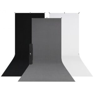 Westcott X Drop 3 Pack Sweep Backdrop Kit (1.5m x 3.7m) sisältää mustat, harmaat ja valkoiset taustat, jotka on asetettu vierekkäin ja joissa on loiva pohjan kaari ja taitettu kolmijalkainen jalusta mustan taustan edessä.