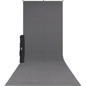 1573368305_308 Westcott X Drop Wrinkle Resistant Backdrop Kit, neutraali harmaa (1,5 m x 3,7 m) näkyy ulottuvan seinältä lattialle, ja sen musta kantolaukku, jossa on olkahihna, on sijoitettu taustan vasemmalle puolelle.