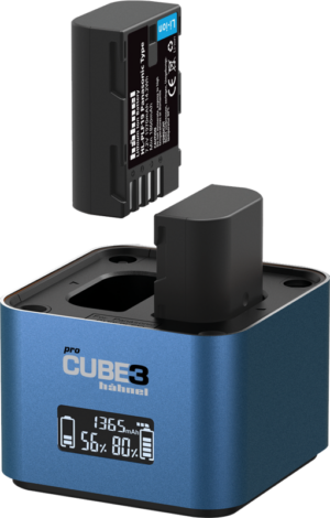 Pienikokoinen sininen Hähnel ProCube 3 Twin Charger Panasonic -latauslaite, jossa on LCD-näyttö ja joka lataa kameran akkua toisessa sen kahdesta latauspaikasta. Näytössä näkyy akun prosenttiosuus ja lataustila.
