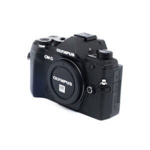 Olympus E-M5 III-5 Olympus E-M5 Mark III (SC 7000) - Käytetty mustan värinen digitaalikamera on kuvattu valkoisella pohjalla, ja sen rungon suojus on paikallaan ilman objektiivia.