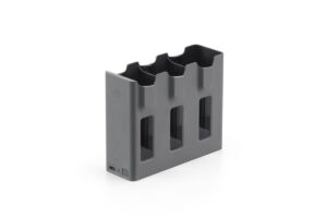 13e5f429d2e235939e6991c9300d49af@large DJI Mavic 4 Pro Parallel Charging Hub -lataustelakka on harmaa, suorakulmainen latauskeskitin, jossa on kolme akkupaikkaa, joissa jokaisessa on pystysuuntaiset aukot, ja latausportti vasemmalla alhaalla, kuvassa tavallisella valkoisella pohjalla.