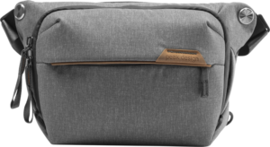 800q-01_123314 Peak Design Everyday Sling 3L v2 Ash -mallistossa on vetoketjullinen etutasku, nahkainen korostus ja säädettävä olkahihna, kuvassa valkoisella pohjalla.