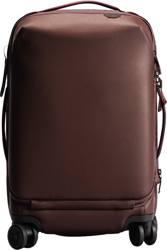 Peak Design Roller Pro Carry-On, punainen, on punainen kovakuorinen matkalaukku, jossa on neljä pyörää, yläkahva ja tyylikäs, minimalistinen muotoilu.